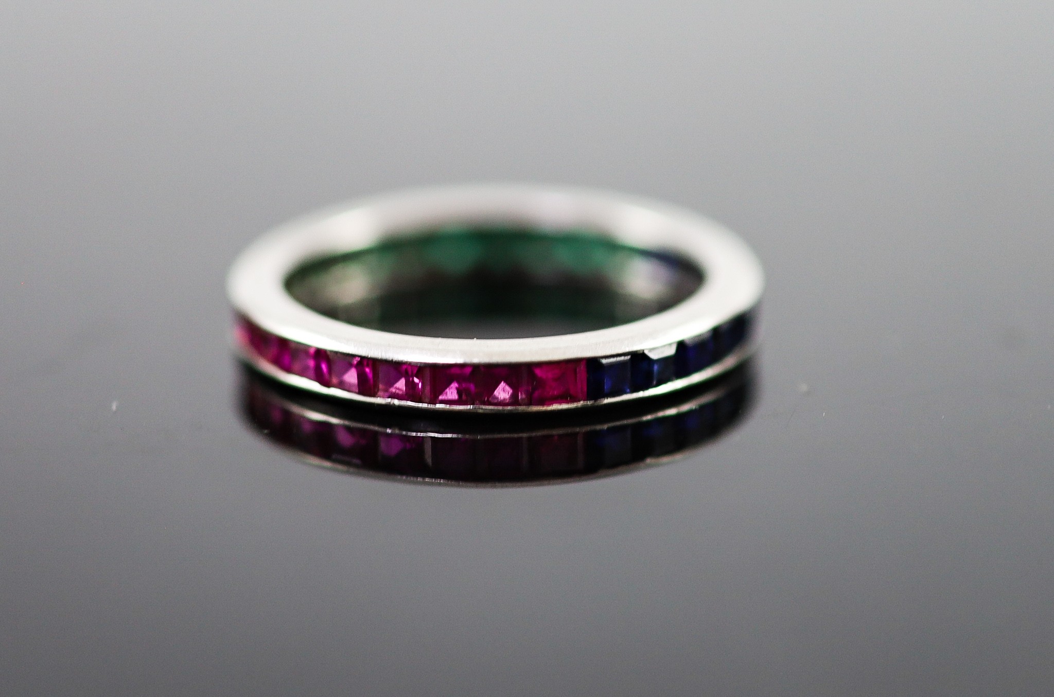A platinum? ruby, emerald and sapphire set full eternity ring